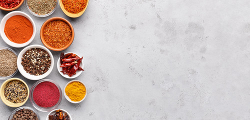 Spices and condiments in bowls on grey background - obrazy, fototapety, plakaty