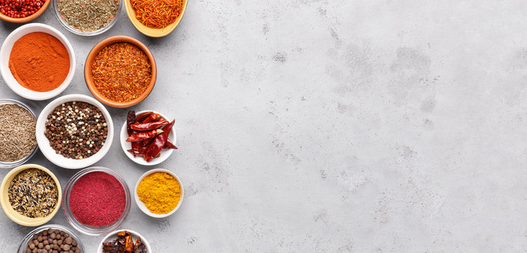 Spices and condiments in bowls on grey background