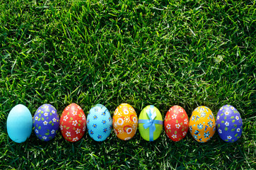 Easter eggs lying on green spring grass arranged in one lane. Space for text