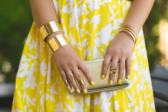 Unrecognizable woman holding wallet in her hands. Lady`s hands wearing rings and accessiories. Girl in yellow dress