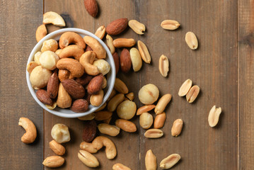 salted cocktail nuts in cup on wood