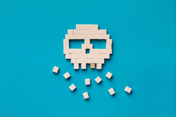 Fototapeta na wymiar Skull made from sugar cubes on blue background
