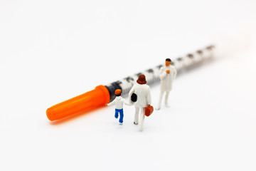 Miniature people: Mother and children meet doctor with syringe. Health care and business concept.