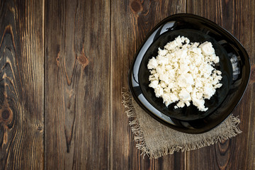 Cottage cheese on blue plate on wooden background.
