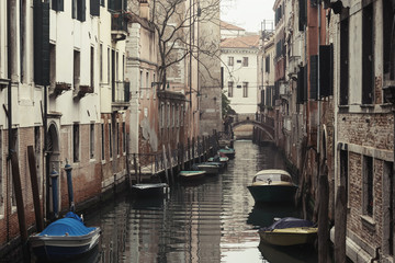 Fototapeta na wymiar Morning view on narrow water canal with rows of boats floating along the walls of houses in Venice, Italy