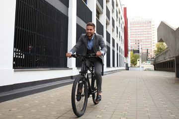 Handsome young businessman riding bicycle outdoors in the city.