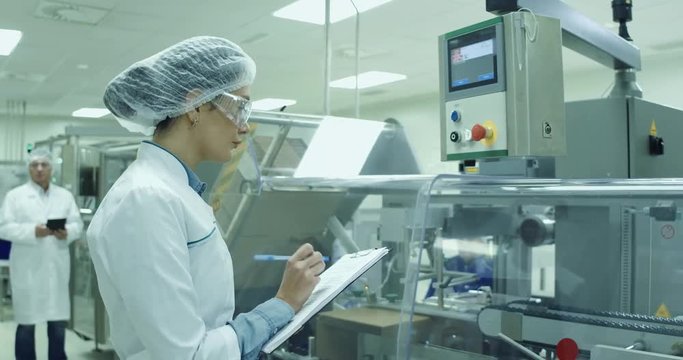 A female technician is monitoring the process on medicine factory.