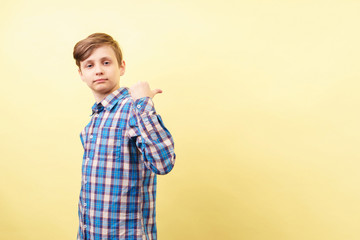 confident boy pointing to object or text behind his back. advertisement or product placement, banner or poster template, emotion facial expression, people reaction