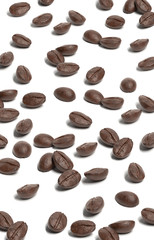 Group of many coffee beans spread on white surface.