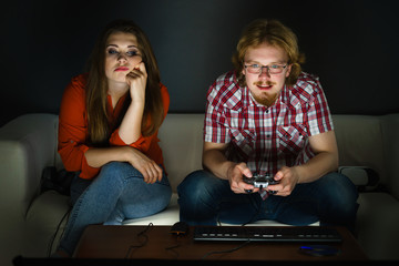 Woman is bored while man playing games