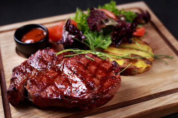 grill and barbeque, meat restaurant menu, juicy medium rare ribeye steak served with vegetable salad and potatoes on board, traditional american cuisine