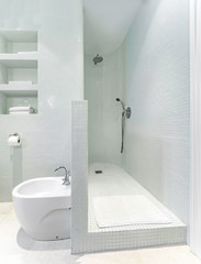 Clean bright bathroom interior with modern shower and white tiles.