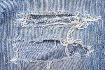 Texture blue jeans with ripped on background, hole and white threads destroyed patterns on denim