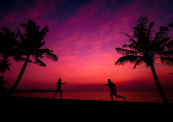 Silhouette of couple on tropical beach during sunset on background of palms and sea