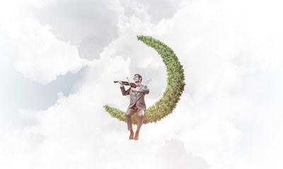 Handsome violinist on moon in blue sky play his melody