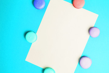 Blue background with white A4 paper and macaroons