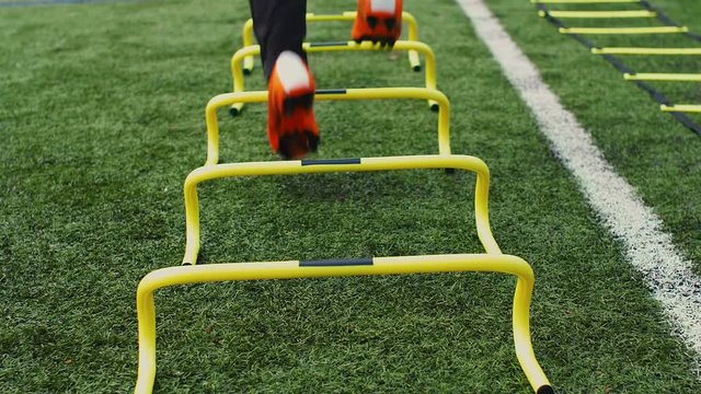 Soccer agility training equipment. Professional football player with training hurdles. 4k slow motion