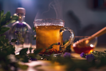 Black tea in a transparent mug, violet flowers, beautiful dark b