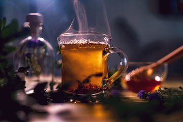Black tea in a transparent mug, violet flowers, beautiful dark blurry background
