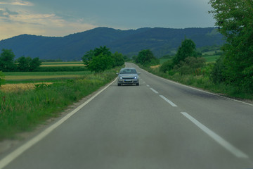 car goes on twisting highway against mountains and wood