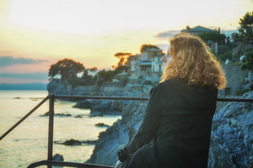 schöne junge rothaarige Frau,im Profil an der Küste im Fischerdorf in Ligurien, Italien genießt den Sonnenuntergang