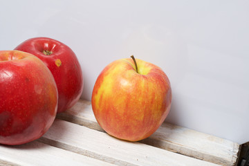 Ripe juicy apples. They lie on a wooden box. On a white background.