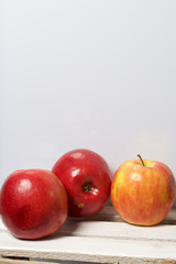 Ripe juicy apples. They lie on a wooden box. On a white background.
