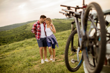 Loving couple stnding next to the car with bicycles