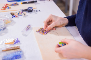 Professional jewelry designer making handmade brooch with beads in studio, workshop. Fashion, creativity and handmade concept