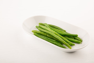 Green Bean in plate, side view isolated on white background, copy space