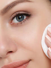 Portrait of young beautiful woman cleaning makeup from her face with cosmetic pad. Cleaning face,...