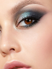 Fototapeta premium Close up beauty portrait of young woman with beautiful fashion makeup. Modern fashion makeup. Colorful smokey eyes. Studio shot. Extreme closeup, partial face view