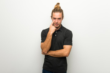 Blond man with long hair over white wall looking to the front