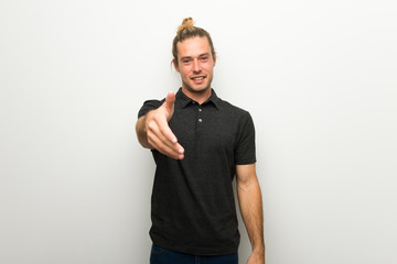 Blond man with long hair over white wall shaking hands for closing a good deal