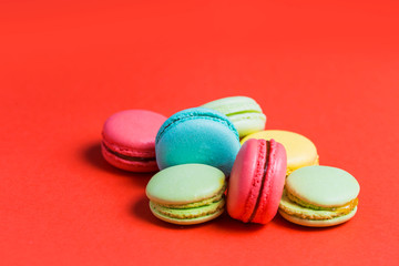Fototapeta na wymiar Close-up of sweet green, yellow, coral, blue macaroons on red background
