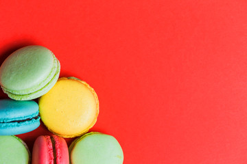 Fototapeta na wymiar Closeup of red background for copy space with colorful macaroons in the corner.