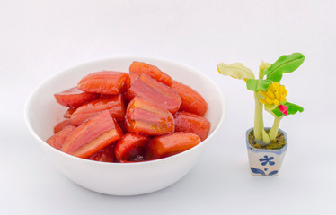 Red Pisang Awak Banana in sugar syrup. Thai style very sweet dessert in a white cup with banana tree Clay sculpture.