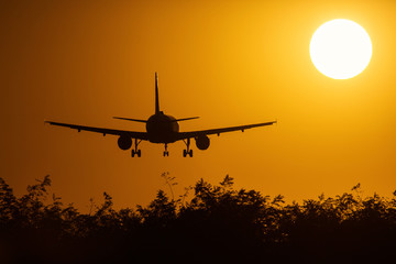 Silhouette of an air plane over the sun with beautiful red clouds in background