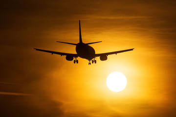Silhouette of an air plane near to the sun with beautiful red clouds in background