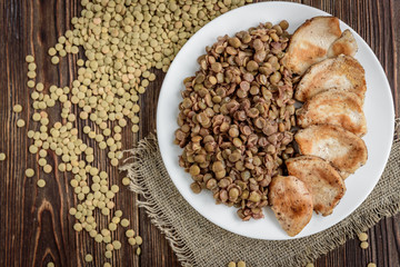 Grilled chicken with lentils on white plate. Healthy dinner