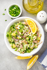 Salad with tuna, avocado, onion, egg and lemon. Spring healthy delicious lunch on light background