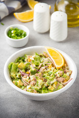 Salad with tuna, avocado, onion, egg and lemon. Spring healthy delicious lunch on light background