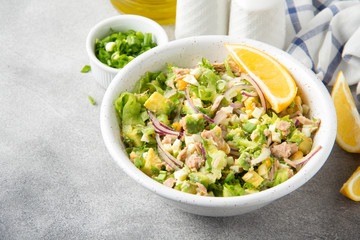 Salad with tuna, avocado, onion, egg and lemon. Spring healthy delicious lunch on light background