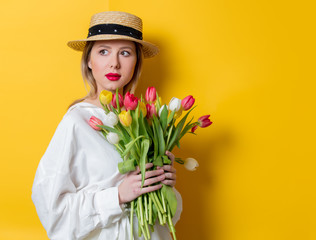 woman in white shirt and hat with fresh springtime tulips