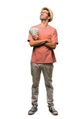 Man holding many bills looking up while smiling on isolated white background