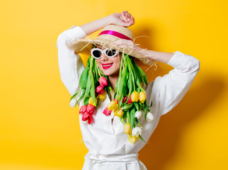 woman in white shirt and hat with fresh springtime tulips and sunglasses