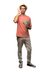 Man holding many bills showing a sign of closing mouth and silence gesture on isolated white background