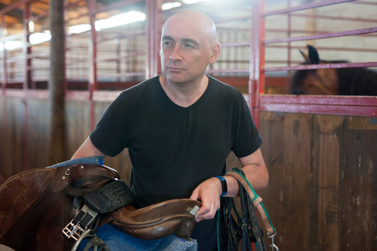 Mature man holding seats and standing at farm with horse