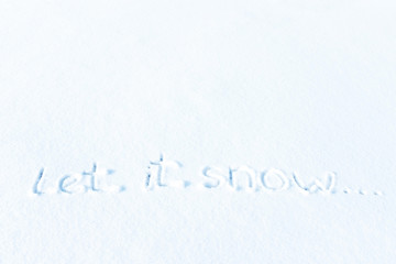 Closeup text LET IT SNOW written on snow