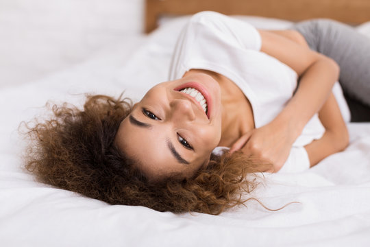 Happy woman lying on bed and looking at camera